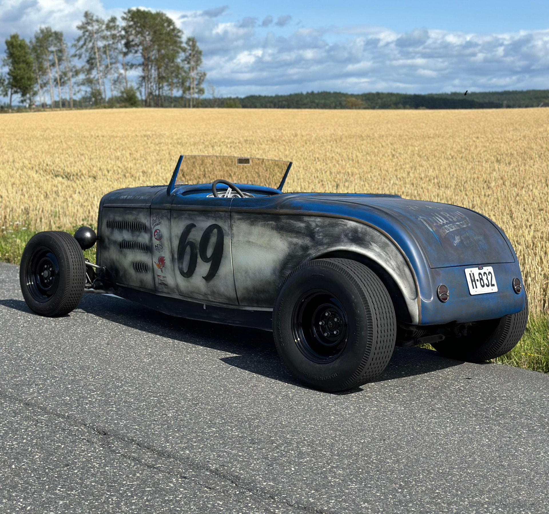 Rear three-quarter view of the '32 Ford Roadster by a wheat field