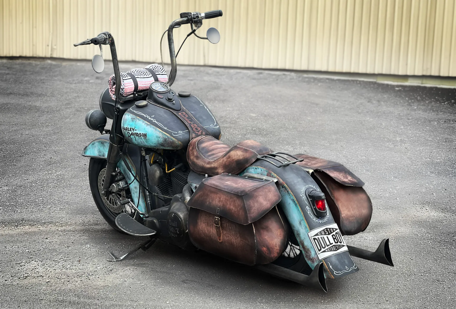 Cholo Bagger custom motorcycle — a 1990 Harley-Davidson FLHS with weathered turquoise paint, hand-made leather saddlebags and ape-hanger bars.