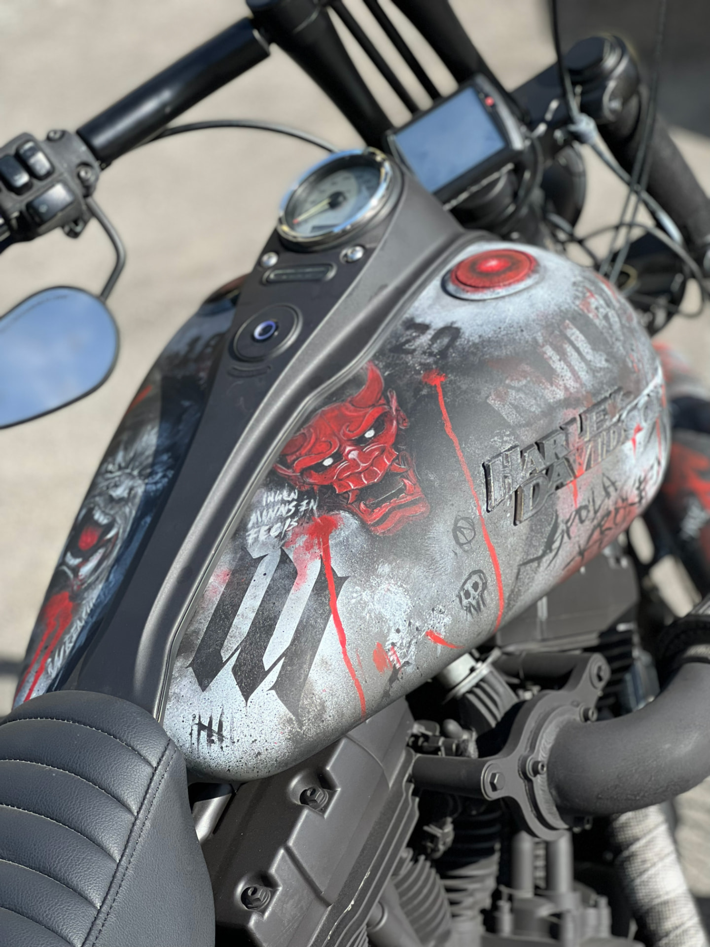 Hand-painted Hannya mask and lettering on a raw metal Harley tank
